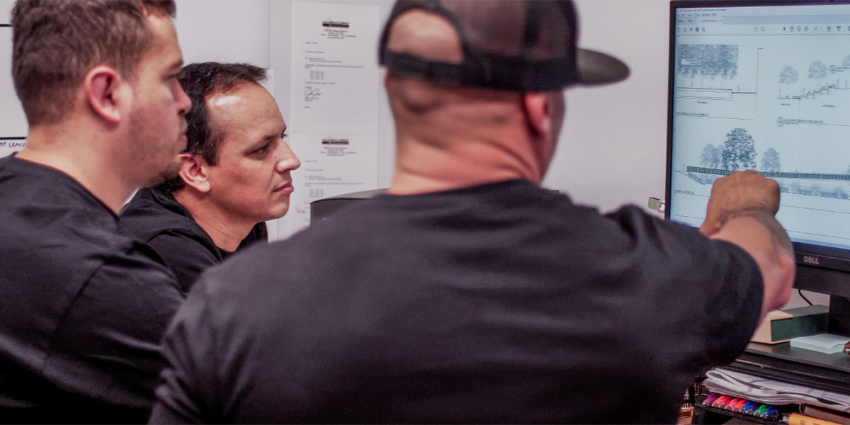 Three engineers in black shirts discussing landscape Design-Build plan