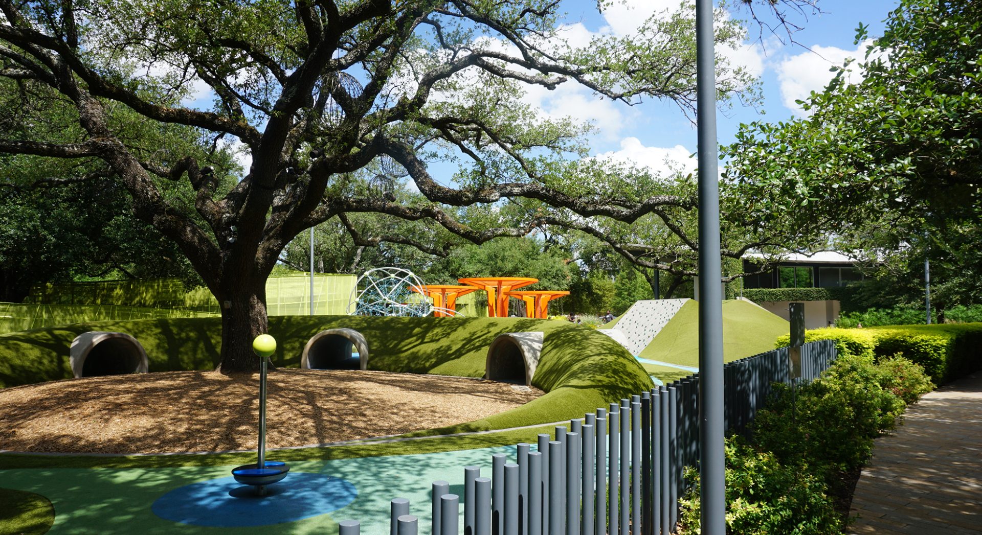 Colorful and playful space at Levy Park featuring unique orange play structures installed by Renfrow+Co