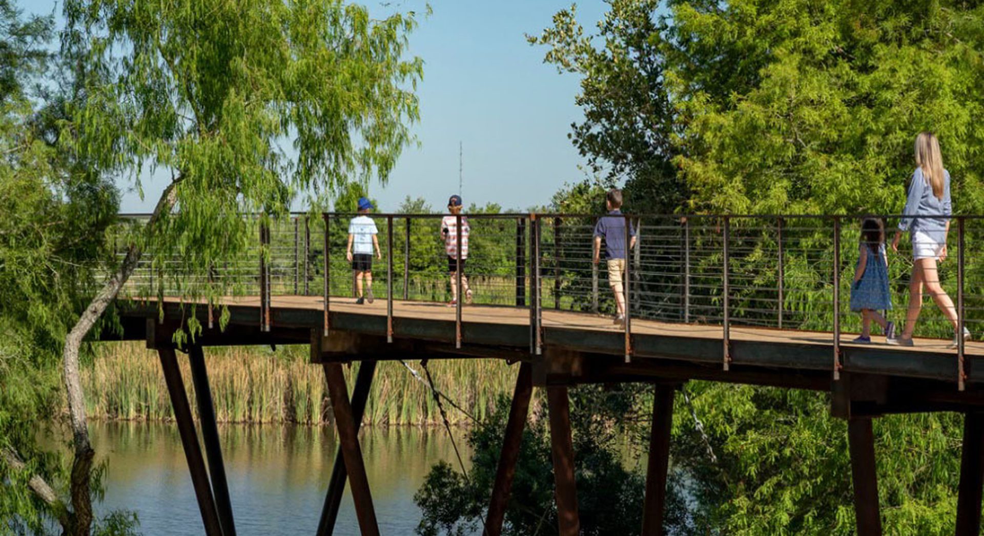 A group of visitors standing on the weathering steel and wooden deck, part of Renfrow+Co's High Island Sky Walk project, with a scenic view of the surrounding lake