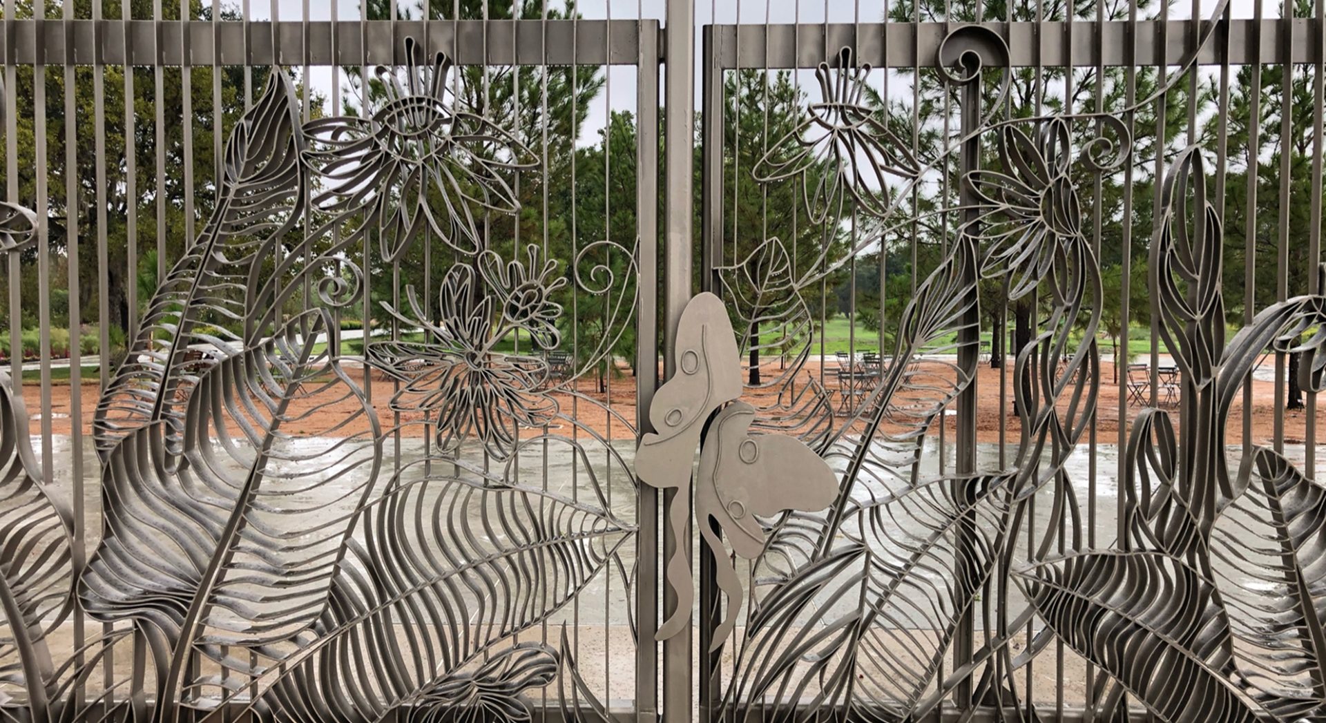 Custom metal gate crafted by Renfrow+Co, featuring intricate botanical patterns and a butterfly detail at the Houston Botanic Garden