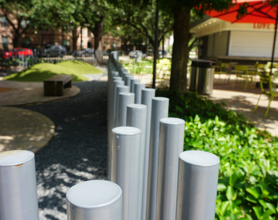 A close-up view of cylindrical silver poles designed and installed by Renfrow+Co as part of the fencing at Levy Park's recreational area