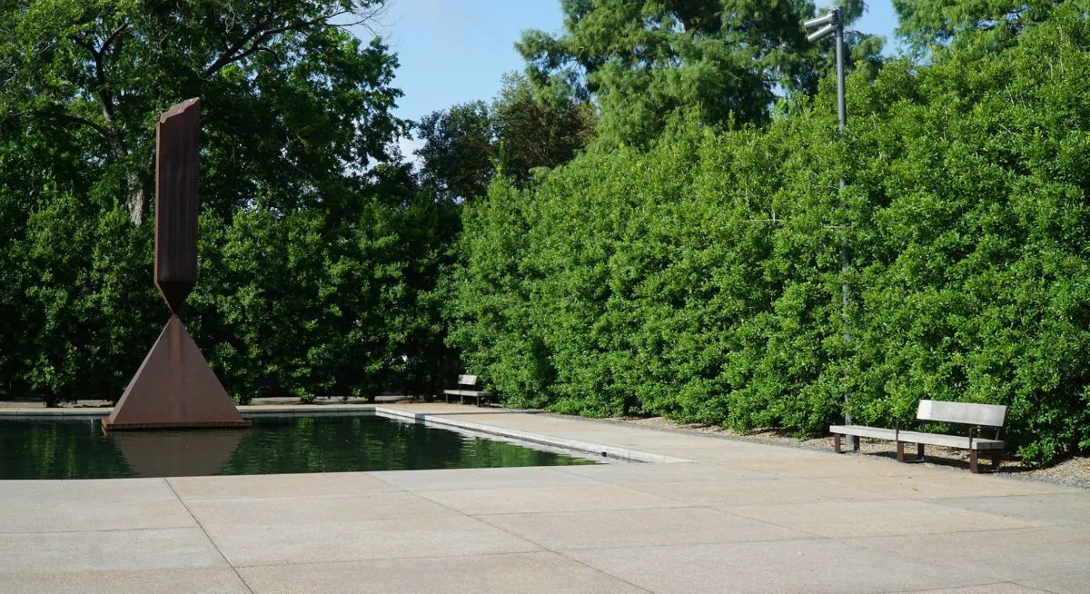 Reflecting pool and sculpture at Rothko Chapel, with a Renfrow+Co-crafted wooden bench placed along the tree line Reflecting pool and sculpture at Rothko Chapel, with a Renfrow+Co-crafted wooden bench placed along the tree line