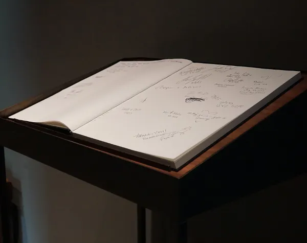 Close-up of a guestbook on a custom-built wooden stand crafted by Renfrow+Co for Rothko Chapel, with signatures and messages written by visitors Close-up of a guestbook on a custom-built wooden stand crafted by Renfrow+Co for Rothko Chapel, with signatures and messages written by visitors