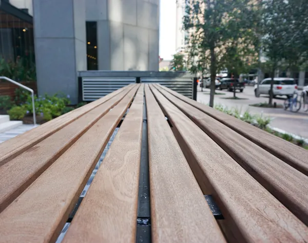 Close-up view of wooden bench slats fabricated and installed by Renfrow+Co at JPMorgan Chase Tower outdoor space Close-up view of wooden bench slats fabricated and installed by Renfrow+Co at JPMorgan Chase Tower outdoor space
