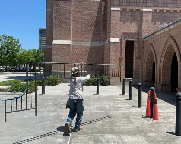 Renfrow+Co team member transporting a custom-fabricated metal railing piece across the courtyard area of St. Martin’s Episcopal Church Renfrow+Co team member transporting a custom-fabricated metal railing piece across the courtyard area of St. Martin’s Episcopal Church